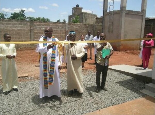 Padre Fabien, circondato dal Consiglio provinciale, da alcuni padri SMA e suore NDA, fra cui la Provinciale, dal personale e da un gruppo di amici, mentre benedice il Centro e, tagliando il nastro, inaugura ufficialmente la struttura